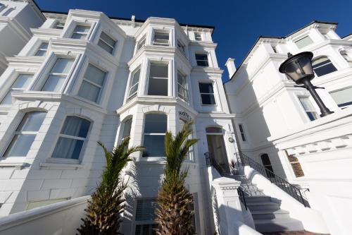 a white house with palm trees in front of it at The Halcyon in Eastbourne