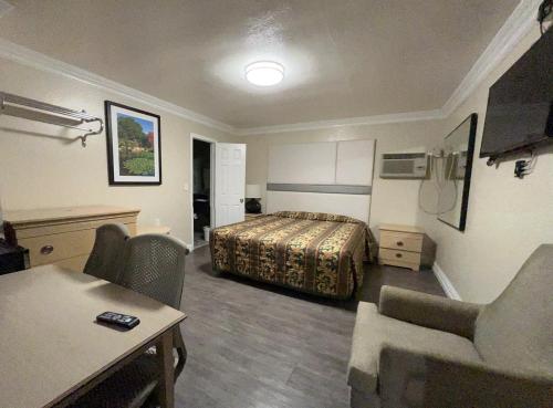 a hotel room with a bed and a table and chairs at Flamingo Motel Oxnard in Oxnard