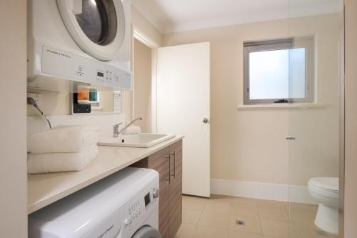 een badkamer met een wastafel en een wasmachine bij Airport Apartments by Vetroblu in Perth