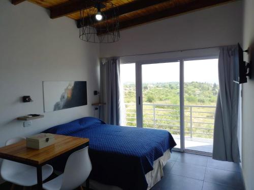 Un dormitorio con una cama y una mesa y una ventana. en Complejo Joansa, en Villa Santa Cruz del Lago