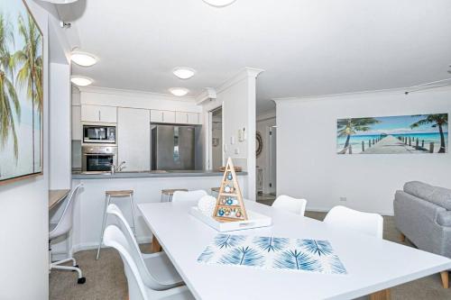 a dining room and kitchen with a white table and chairs at Broadbeach Victoria Square in Gold Coast