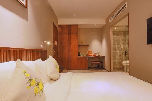 a bedroom with a white bed and a bathroom at CHERRY BOUTIQUE HOTEL in Ho Chi Minh City