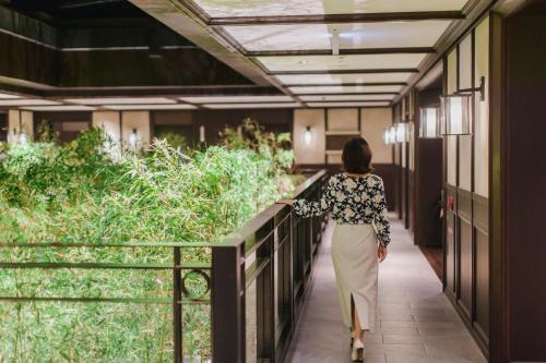 a woman walking down a walkway in a building at Dhawa Yura Kyoto - Banyan Group in Kyoto