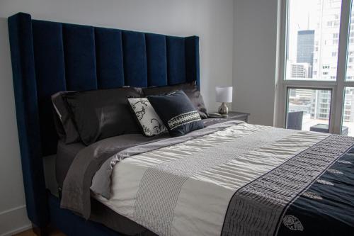 a large bed with a blue headboard in a bedroom at Downtown High-rise Condo- CN Tower View in Toronto