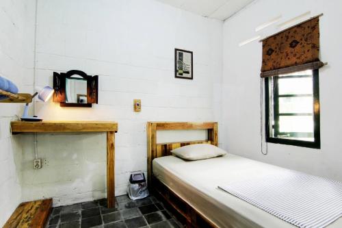 een kleine slaapkamer met een bed en een raam bij Rumah Kita BnB in Yogyakarta