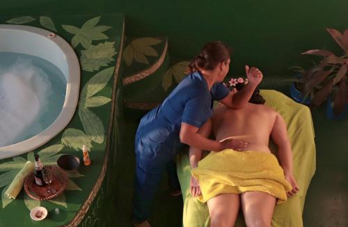 a woman giving a man a bath in a mirror at Eco Hotel El Refugio Boutique in Leticia