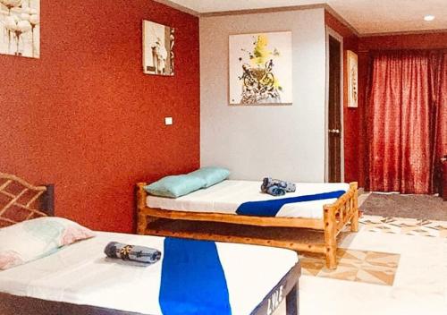 2 letti in una camera con pareti rosse di RedDoorz @ Thomasville Inland Resort Brgy. 2 a Hinoba-an