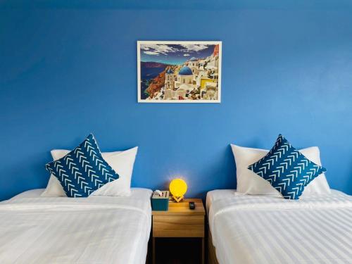 two beds in a room with blue walls at Bleu Marine Sattahip Hotel in Ban Nong Sa