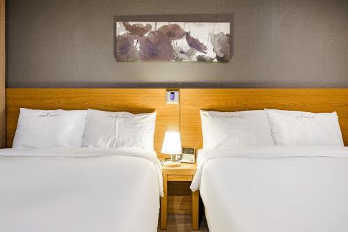 two beds in a hotel room with white pillows at Lamer Hotel in Busan