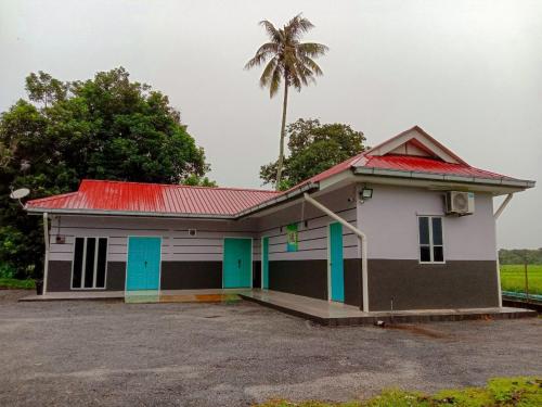 a small house with a palm tree behind it at D'Merbok Homestay in Kampong Merbok