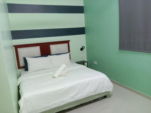 a bedroom with a bed with white sheets and blue walls at D'Merbok Homestay in Kampong Merbok