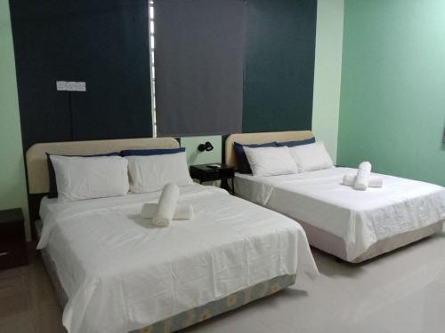 duas camas com lençóis brancos num quarto em D'Merbok Homestay em Kampong Merbok