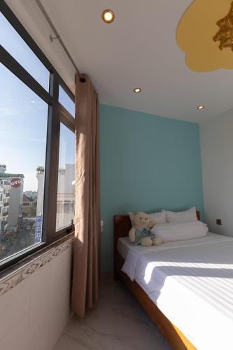 a bedroom with a bed with a teddy bear next to a window at 26 Topaz Hotel in Vung Tau