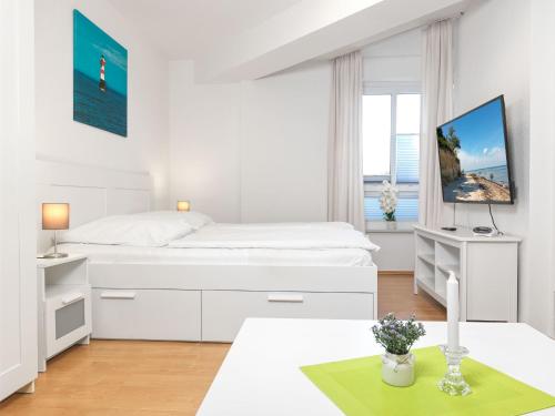 a white bedroom with a bed and a desk at Haus Seeblick Steuerbord in Insel Poel