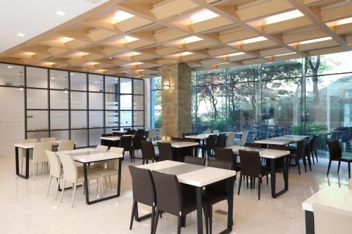 The K Jirisan Family Hotel في Gurye: مطعم بطاولات وكراسي ونوافذ كبيرة