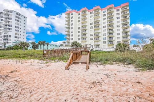 a boardwalk on the beach in front of a building at Sand and Sea Enjoyment Retreat in Ormond Beach