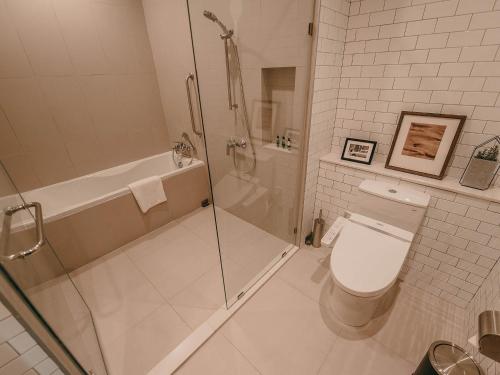 a white bathroom with a shower and a toilet at Oakwood Hotel & Residence Sri Racha in Si Racha