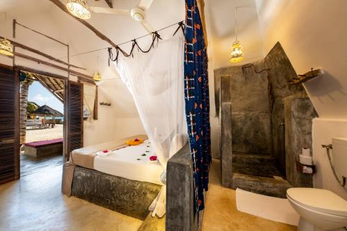 a bathroom with a bed and a toilet in a room at Nur Beach Hotel in Jambiani