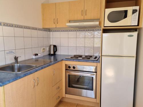 a small kitchen with a sink and a microwave at Seaview Motel & Apartments in Apollo Bay
