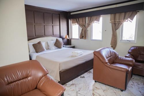 a bedroom with a bed and two leather chairs at Mix Hotel in Ban Hua Thale