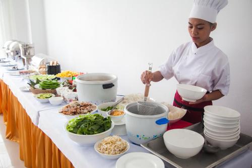 un chef que prepara comida en una mesa en una cocina en Douangchan Plaza Hotel, en Vientiane