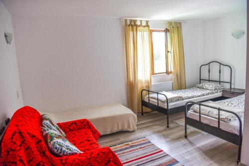 a living room with a red couch and a bed at Pensiunea Silva Home in Luncaviţa