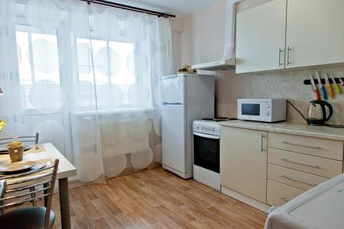 イジェフスクにあるApartments Severny, 54-8のキッチン(白い冷蔵庫、テーブル付)