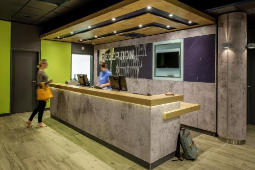 a woman walking past a reception desk in a office at Ibis budget Hamburg City Ost in Hamburg