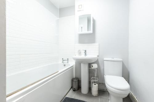 a white bathroom with a toilet and a sink at BEST PRICE! - 1 MIN TO THE SHOPS, BARS, PUBS & RESTAURANTS! PERFECT LOCATION - FREE PARKING - FREE WIFI - SMART TV - COMFY BEDS - 4 Single beds or 2 Doubles in Portsmouth