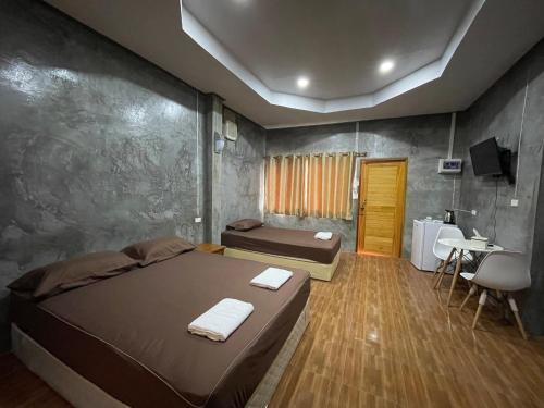 a bedroom with two beds and a table and a television at บ้านภัทร์จรัส น่าน - Baan Patjarad Nan in Ban Fai Kaeo