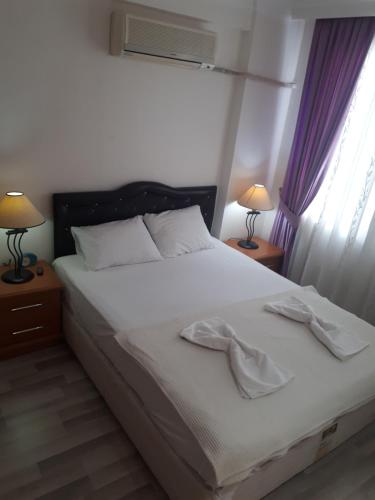 マフムトラールにあるAygun Apartのベッドルーム1室(白いシーツとランプ2つ付)