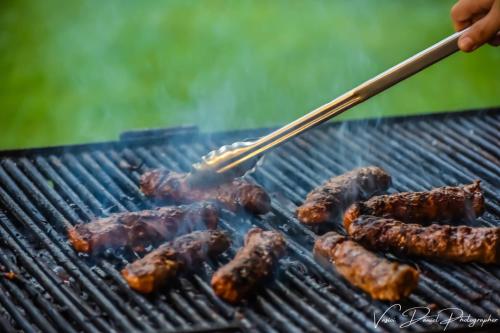 a person is cooking meat on a grill at Pensiunea Silva Home in Luncaviţa