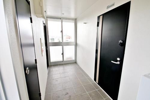 a hallway with two black doors and a tile floor at TOMMY CONDOMINIUM WAKASA 601 in Naha