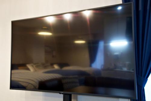 a flat screen tv in a room with a bed at TOMMY CONDOMINIUM WAKASA 601 in Naha