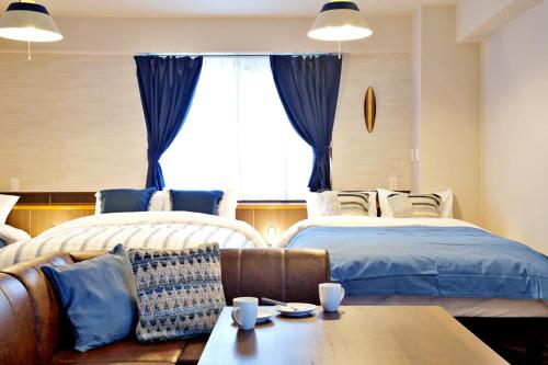 a living room with two beds and a couch at TOMMY CONDOMINIUM WAKASA 601 in Naha