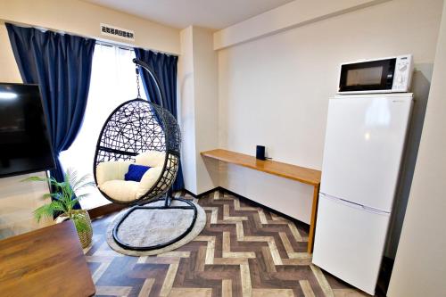 a room with a wicker chair in front of a window at TOMMY CONDOMINIUM WAKASA 601 in Naha