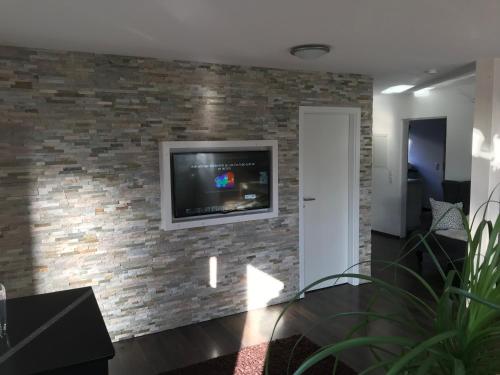 ein Wohnzimmer mit einem TV an einer Backsteinwand in der Unterkunft Ferienwohnung Paradies Hella in Kippenheim