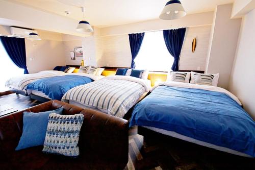 a bedroom with three beds and a couch at TOMMY CONDOMINIUM WAKASA 601 in Naha