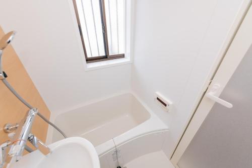 a white bathroom with a toilet and a window at Blue Lagoon in Kamakura