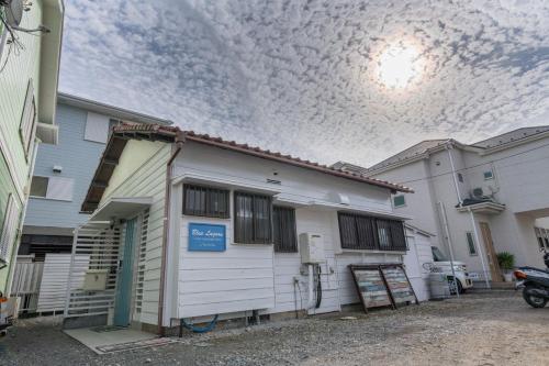 a white house with a cloudy sky above it at Blue Lagoon in Kamakura