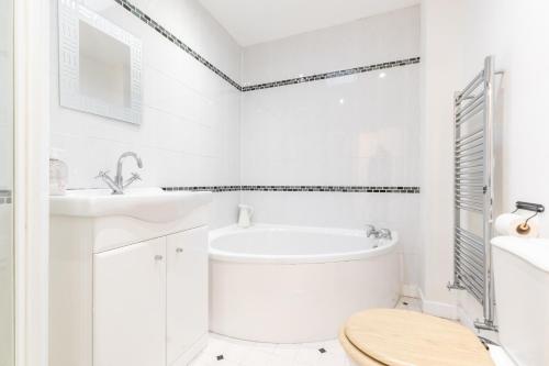 Baño blanco con bañera y lavamanos en BEST PRICE! LARGE HOME FOR 4 - SMART TV - COMFY BEDS - GARDEN - 4 Single Beds or 2 Doubles!, en Portsmouth