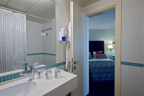 a bathroom with a sink and a mirror and a bed at Metropolitan Hotel in Tel Aviv