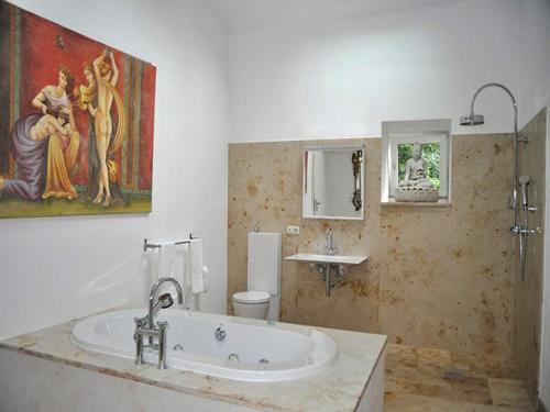 ein Badezimmer mit Badewanne und Waschbecken und einem Gemälde in der Unterkunft Ferienwohnungen Schlosseinkehr in Aschau im Chiemgau