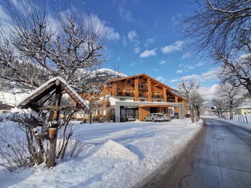 a large wooden house in the snow with a driveway at Hotel Alpina in Rauris