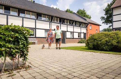 a man and woman walking a dog in front of a building at Buitenplaats De Mechelerhof in Mechelen