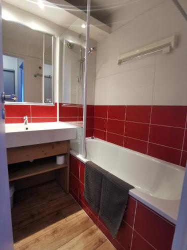La salle de bains est pourvue d'un lavabo, d'une baignoire et de carreaux rouges. dans l'établissement La Tania 309 Le Britania, à Courchevel