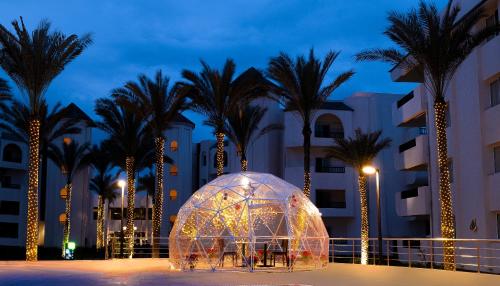 a illuminated igloo in front of palm trees at night at Palma Hotel in Port Said