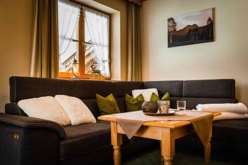 a living room with a black couch and a table at Gästehaus Alpenparadies in Krün