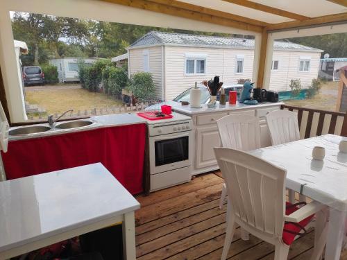 eine Außenküche mit einem Tisch und Stühlen auf einer Terrasse in der Unterkunft Mobil home climatisé au Domaine Lalande à Mimizan in Mimizan