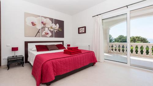 a bedroom with a large bed with a red blanket at Villa Bonaire in Alcudia